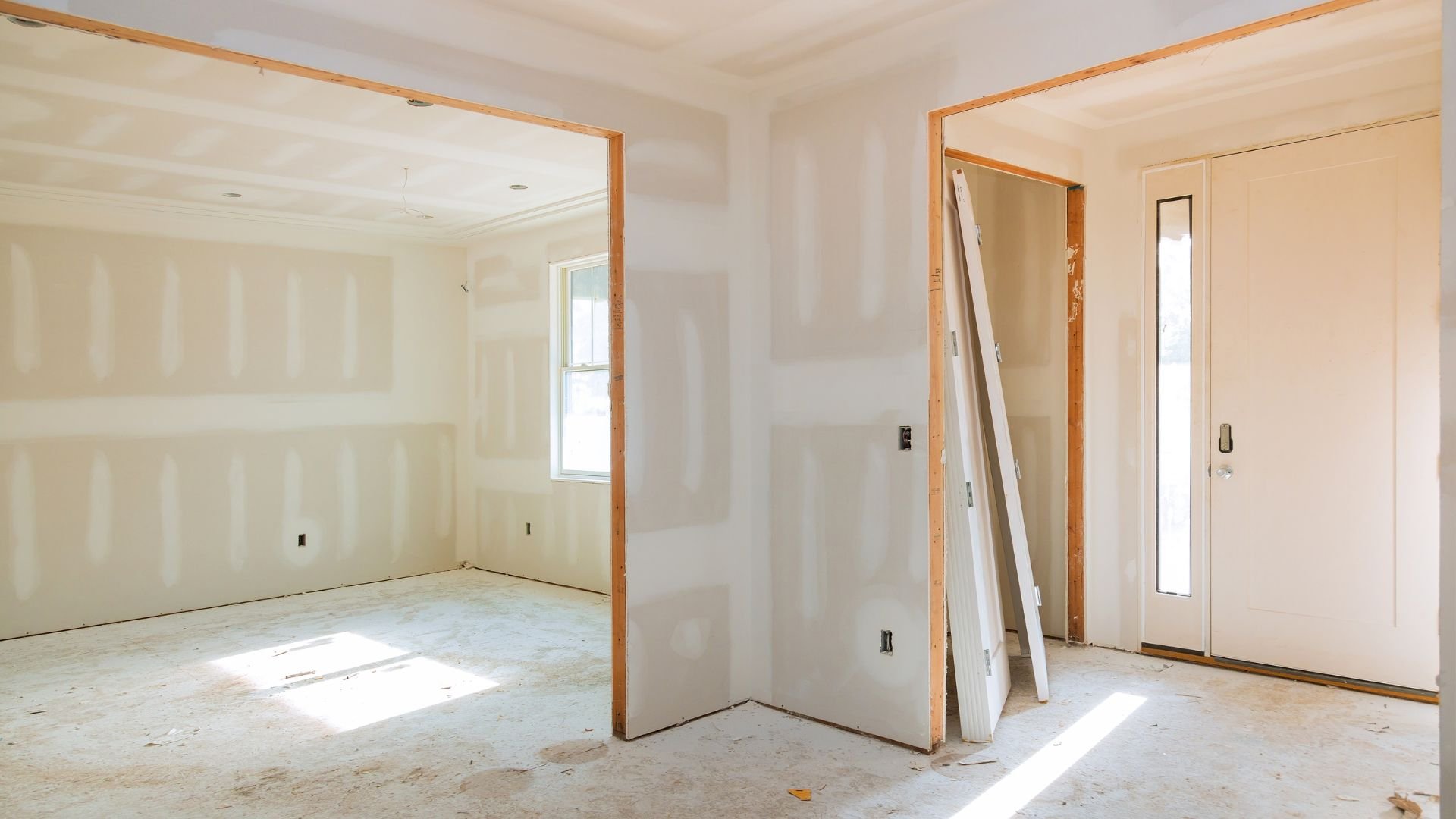 Interior room during renovation with drywall, wooden frames, and construction materials