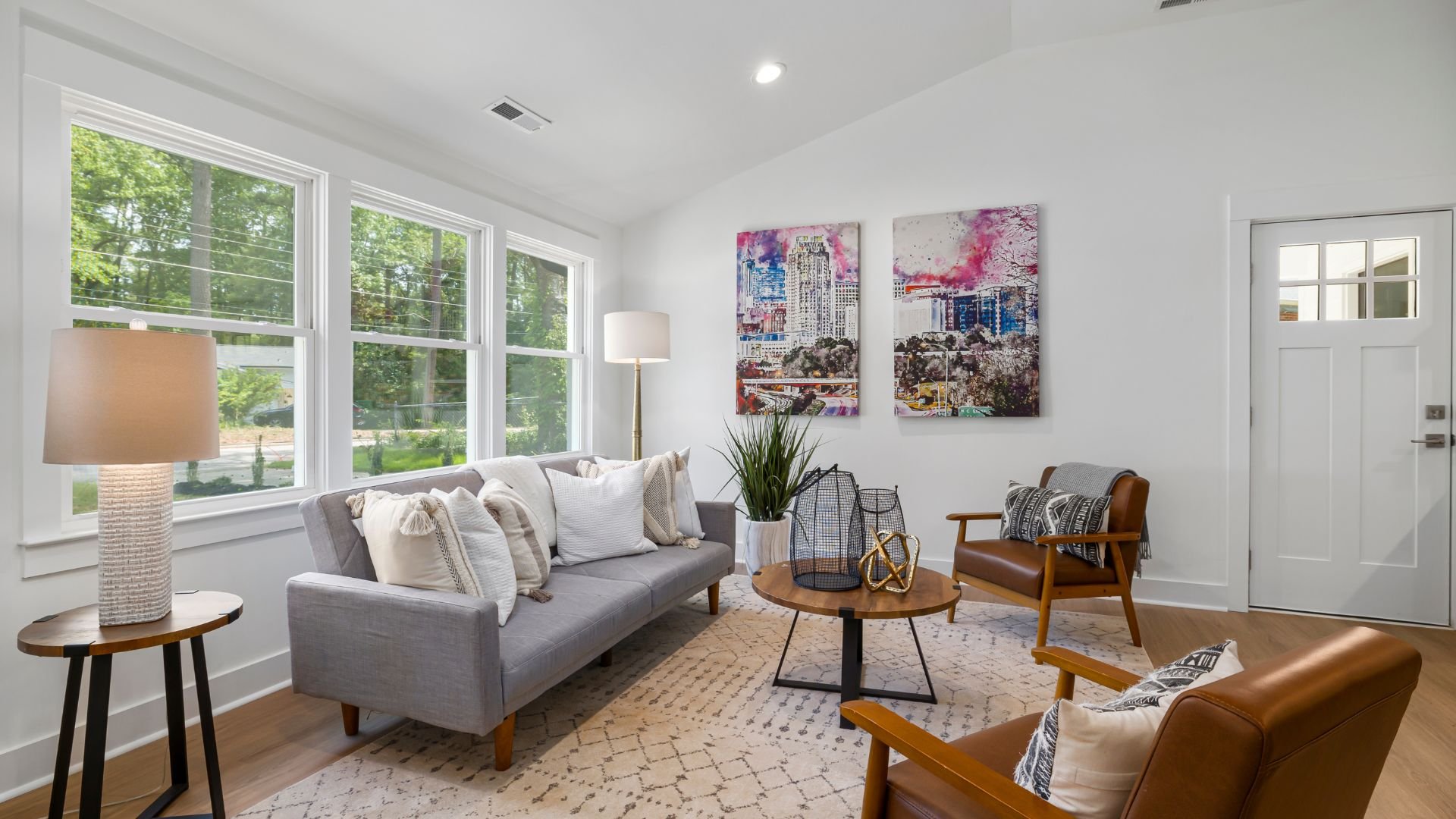 Modern living room with gray sofa, city artwork, and large windows